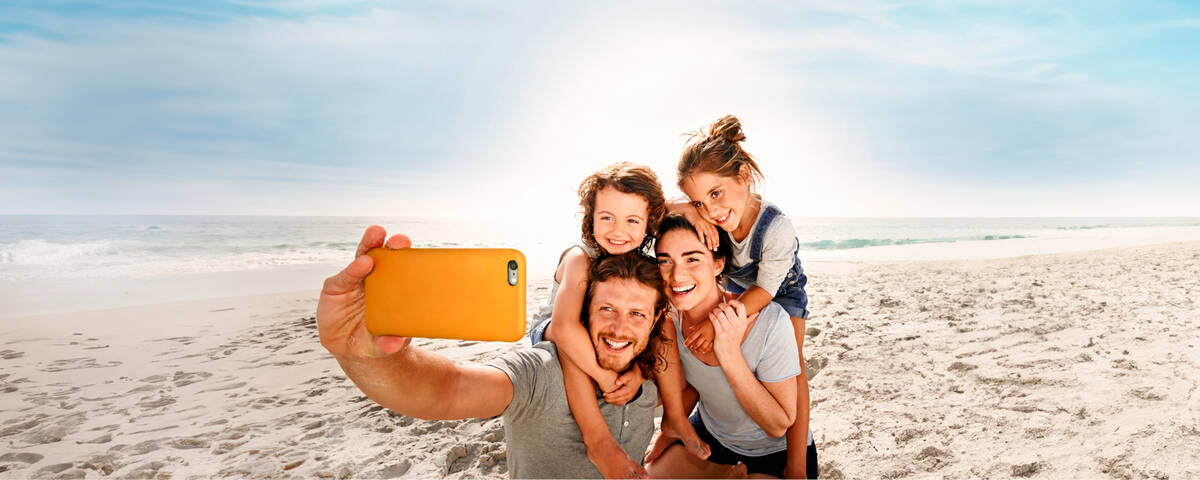 Eine Familie macht ein Selfie am Strand.