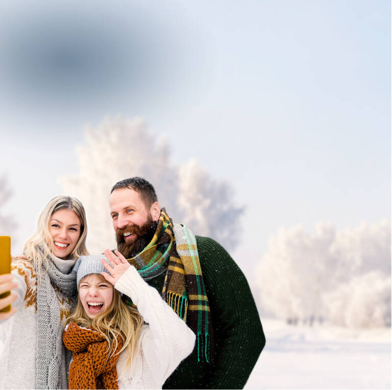Familie macht mit ihrem Handy und günstigen Handyvetrag ein Selfie in der Winterlandschaft
