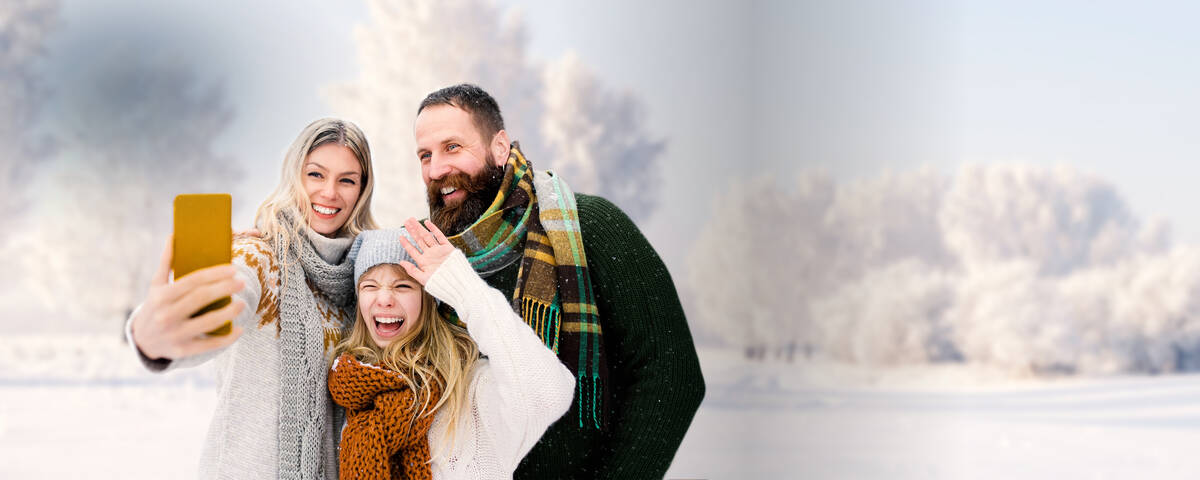 Familie macht mit ihrem Handy und günstigen Handyvetrag ein Selfie in der Winterlandschaft