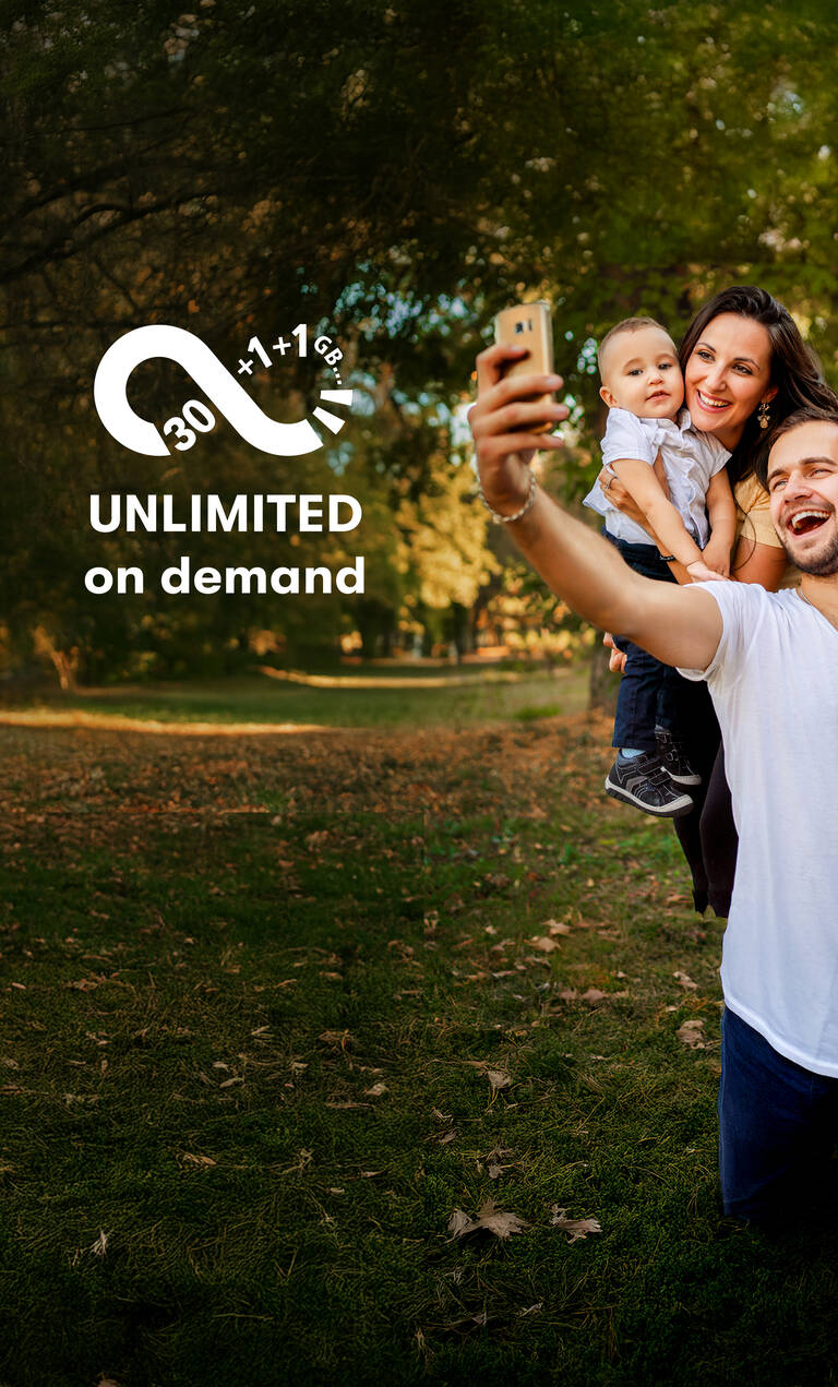 Unbegrenztes Datenvolumen: Vater macht ein Selfie von Familie vor einem Baum.