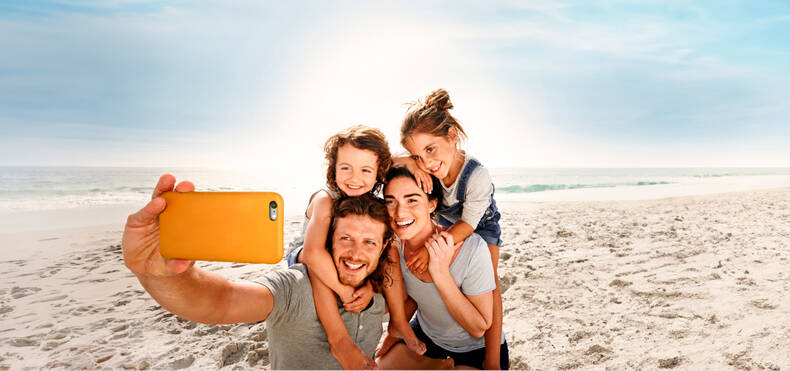 Eine Familie macht ein Selfie am Strand.