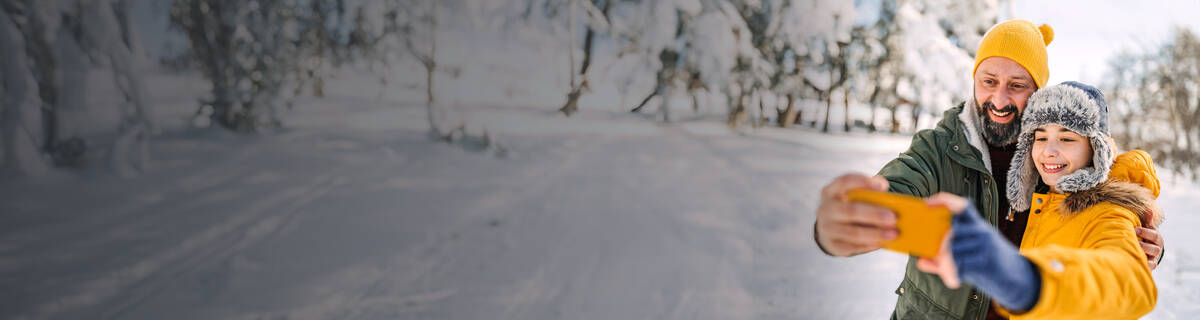 Unbegrenztes Datenvolumen: Vater und Kind in Winterlandschaft machen ein Selfie.